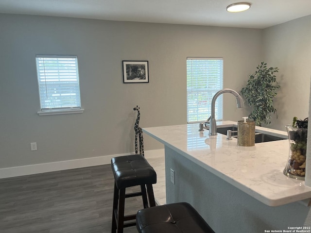 kitchen with a kitchen bar, sink, and dark hardwood / wood-style floors