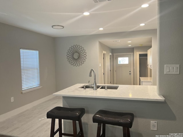 kitchen featuring kitchen peninsula, a kitchen bar, white cabinets, and sink