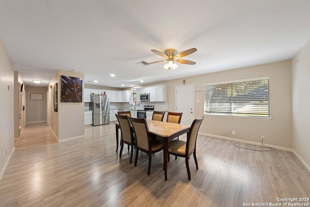 dining space featuring a textured ceiling, light wood-type flooring, and ceiling fan