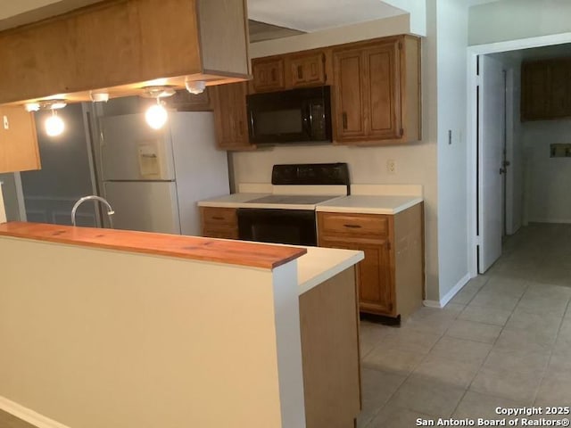 kitchen with kitchen peninsula, light tile patterned floors, white appliances, and sink