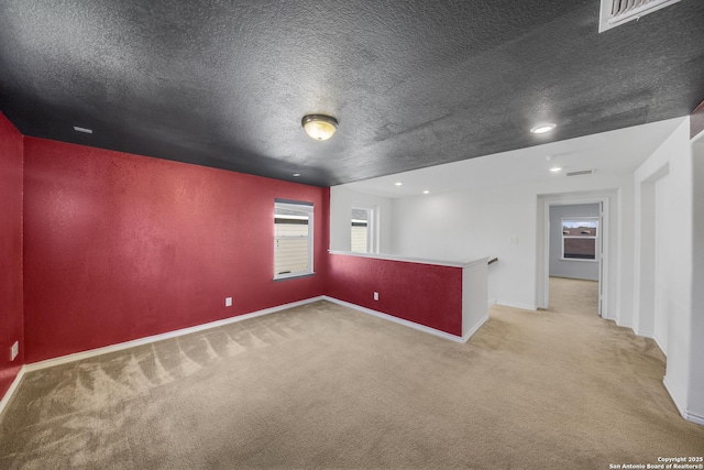 unfurnished room featuring a textured ceiling and light carpet