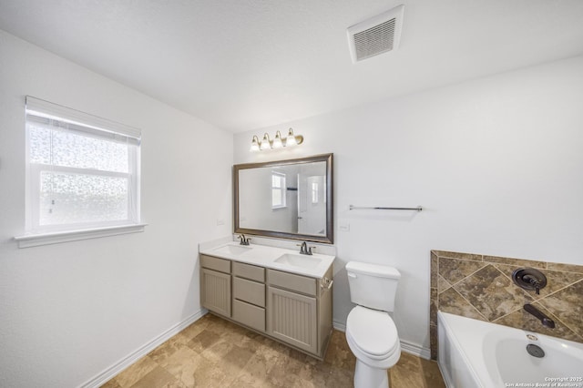 bathroom featuring a washtub, vanity, and toilet