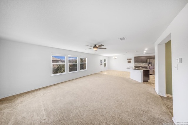 unfurnished living room featuring light colored carpet and ceiling fan