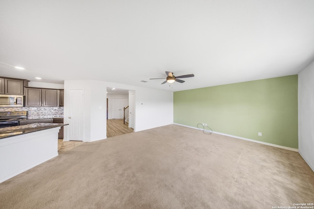 unfurnished living room featuring ceiling fan and light colored carpet