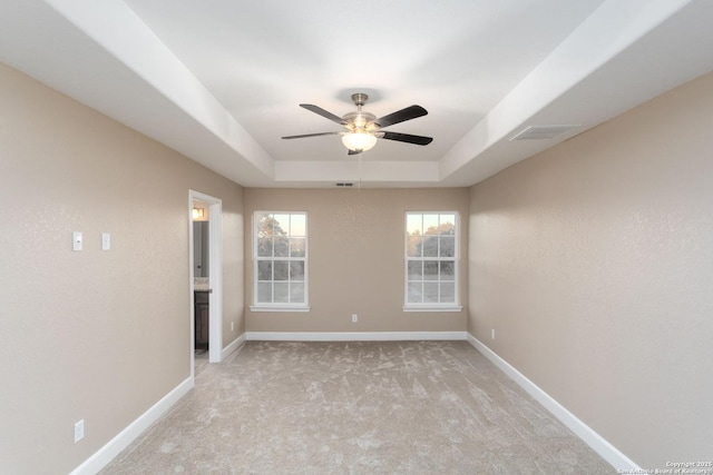 carpeted empty room featuring ceiling fan and a raised ceiling