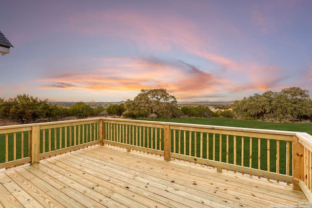 deck at dusk featuring a yard