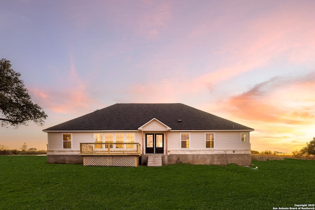 back house at dusk with a lawn and a wooden deck