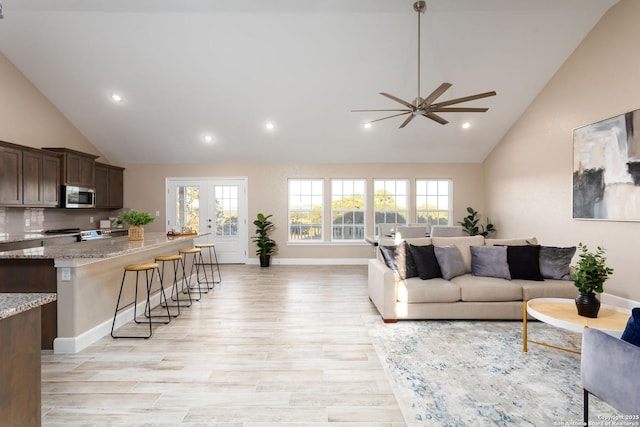 living room with ceiling fan, a healthy amount of sunlight, light wood-type flooring, and french doors