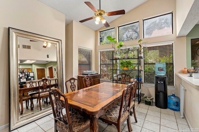 tiled dining space featuring ceiling fan and high vaulted ceiling