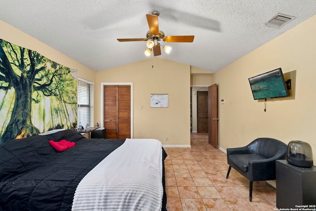 bedroom with vaulted ceiling, ceiling fan, light tile patterned floors, a textured ceiling, and a closet