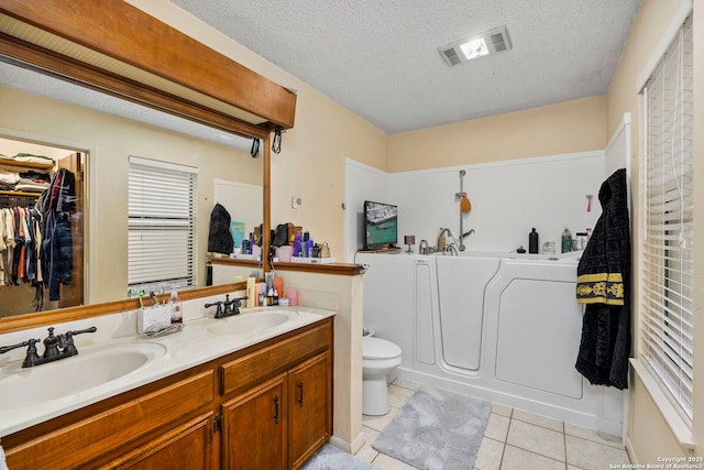 bathroom featuring a washtub, tile patterned floors, a textured ceiling, toilet, and vanity