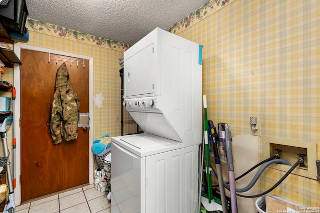 laundry room featuring a textured ceiling, light tile patterned floors, and stacked washer and dryer