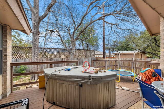 wooden deck featuring a hot tub and a trampoline