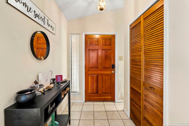 tiled entrance foyer featuring a textured ceiling and lofted ceiling