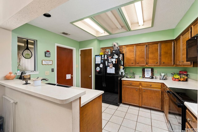 kitchen with black appliances, sink, light tile patterned floors, a textured ceiling, and kitchen peninsula