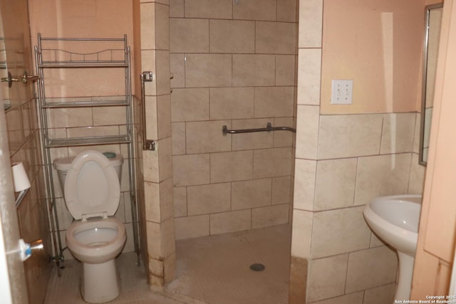 bathroom featuring tiled shower, toilet, and tile walls