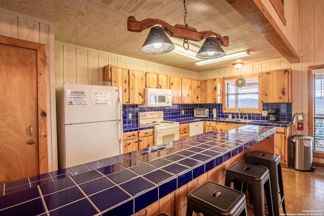 kitchen featuring tile counters, white appliances, sink, and a breakfast bar