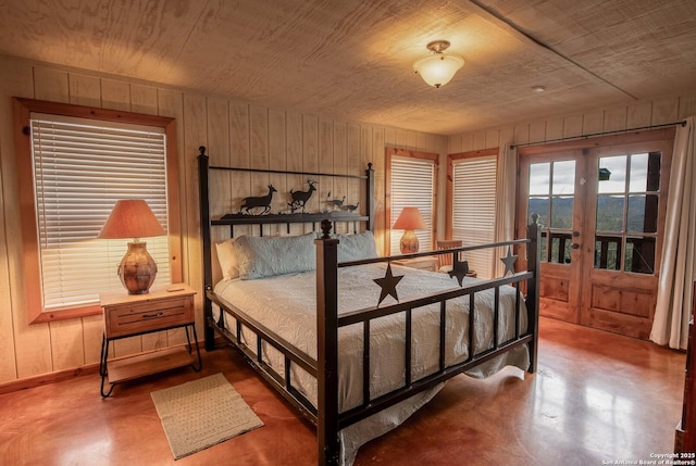 bedroom featuring concrete flooring, wood walls, french doors, and wooden ceiling