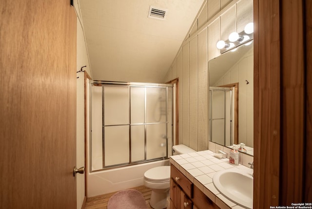 full bathroom with vanity, toilet, lofted ceiling, and enclosed tub / shower combo