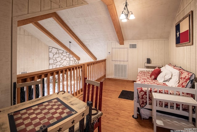 interior space featuring vaulted ceiling with beams, wood walls, wood-type flooring, and an inviting chandelier