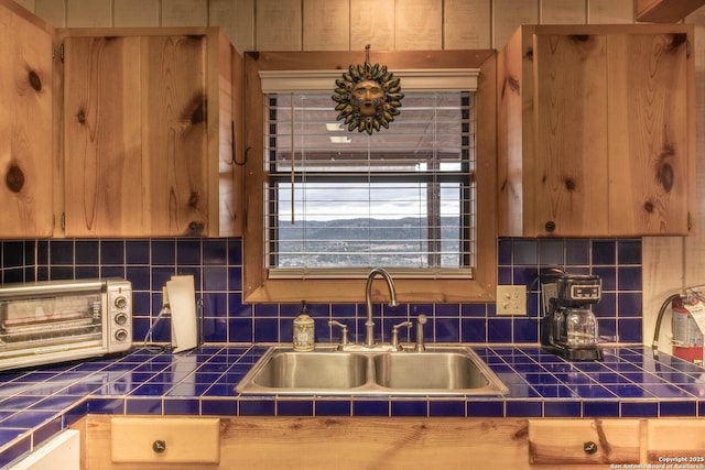 kitchen featuring tile countertops, tasteful backsplash, and sink