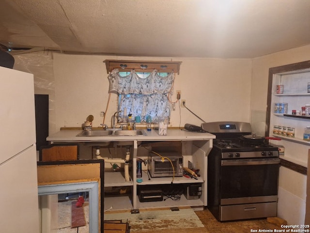 kitchen with gas stove, white refrigerator, and sink