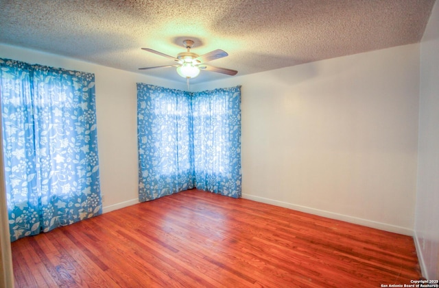 empty room featuring hardwood / wood-style floors, a textured ceiling, ceiling fan, and a wealth of natural light