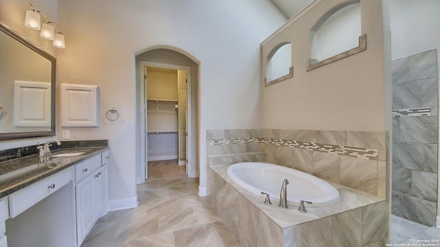 bathroom featuring vanity and tiled tub