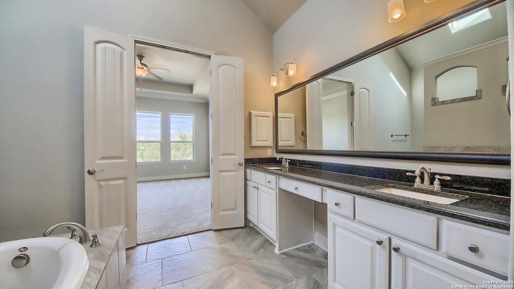 bathroom with a washtub, vanity, ceiling fan, and lofted ceiling