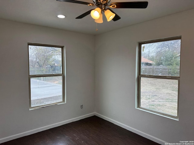 spare room featuring a wealth of natural light, dark wood-type flooring, and ceiling fan