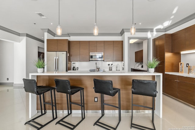 kitchen featuring a breakfast bar, light tile patterned floors, hanging light fixtures, and appliances with stainless steel finishes