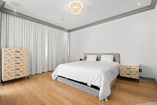 bedroom featuring hardwood / wood-style floors, an inviting chandelier, and ornamental molding