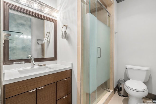 bathroom with tile patterned floors, a shower with door, vanity, and toilet