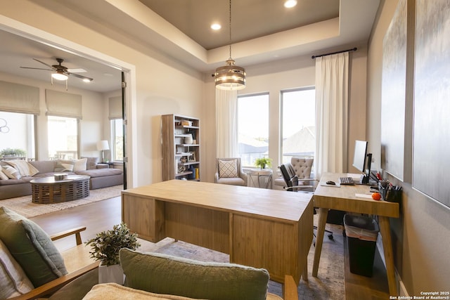 office area with a tray ceiling, ceiling fan with notable chandelier, and dark hardwood / wood-style floors