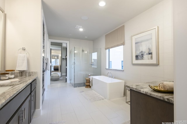 bathroom featuring tile patterned flooring, vanity, separate shower and tub, and tile walls