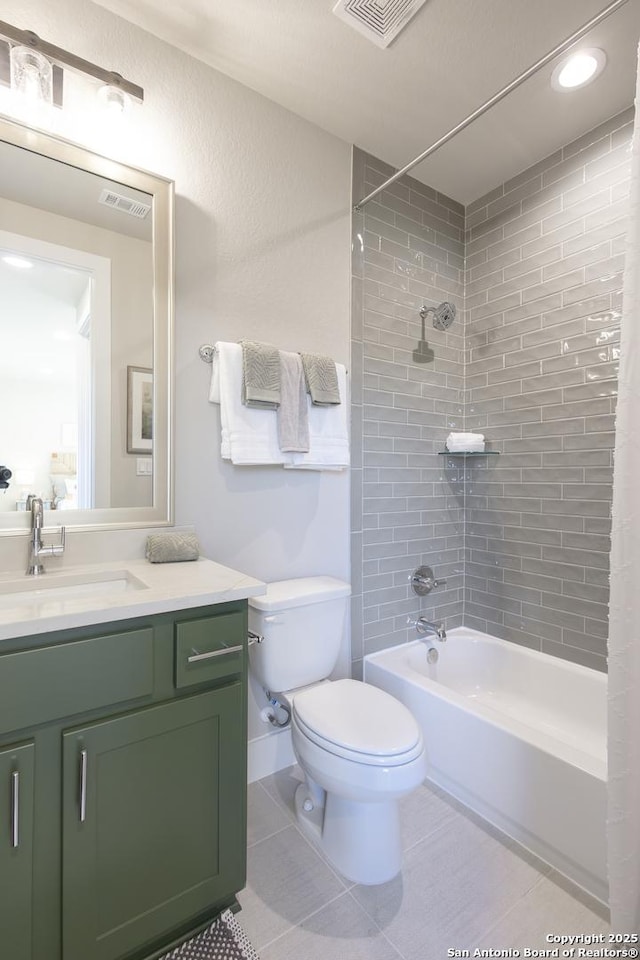 full bathroom with tile patterned flooring, vanity, tiled shower / bath combo, and toilet