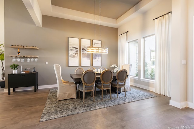 dining area with a chandelier, a tray ceiling, and dark wood-type flooring