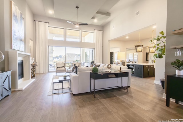 living room with hardwood / wood-style flooring, ceiling fan, and a high ceiling