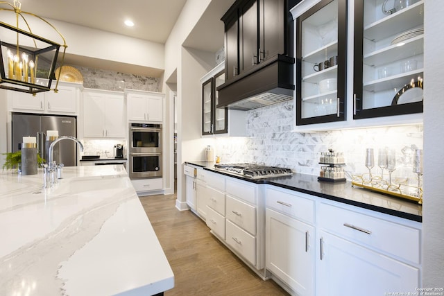 kitchen featuring dark stone counters, white cabinets, sink, appliances with stainless steel finishes, and decorative light fixtures