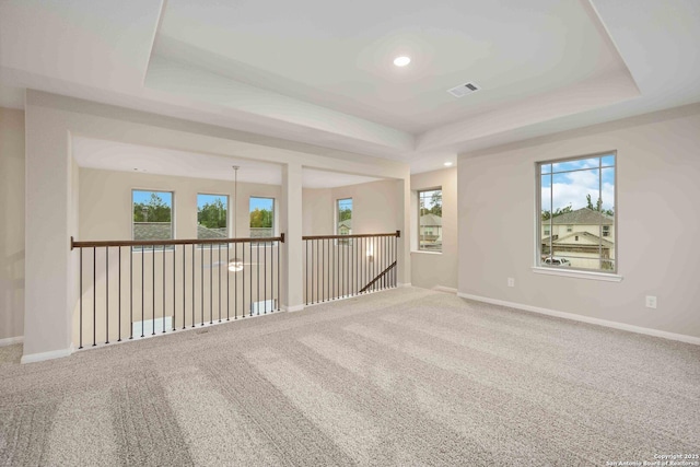 carpeted empty room featuring a raised ceiling