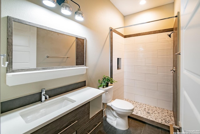 bathroom featuring vanity, tiled shower, and toilet