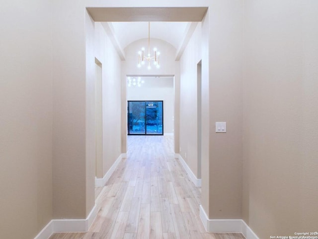 hall with brick ceiling, lofted ceiling, a chandelier, and light hardwood / wood-style floors