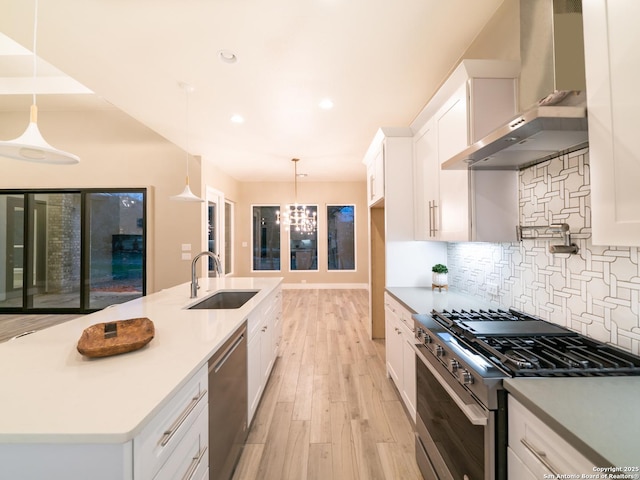 kitchen featuring wall chimney exhaust hood, stainless steel appliances, hanging light fixtures, and white cabinets