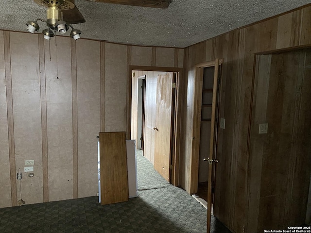 interior space with ceiling fan and wooden walls