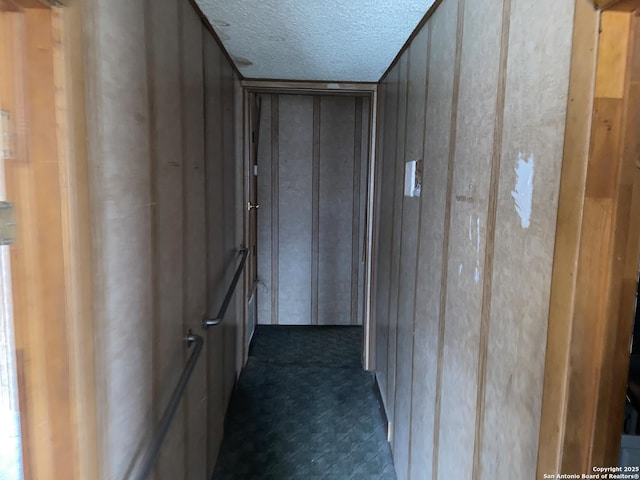 corridor with wood walls and a textured ceiling