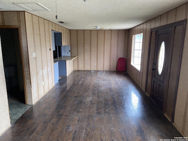 foyer entrance featuring a textured ceiling and dark wood-type flooring