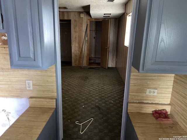 corridor with wood walls and a textured ceiling