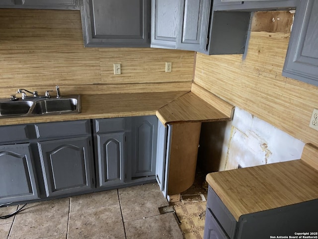 kitchen with gray cabinets, light tile patterned floors, and sink