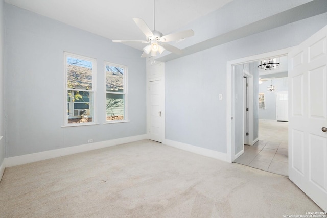 carpeted empty room featuring ceiling fan with notable chandelier