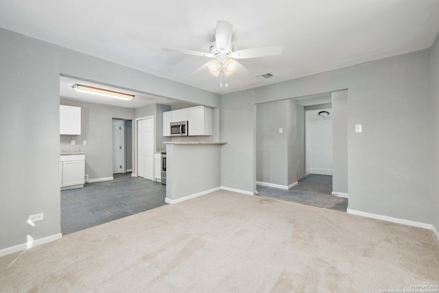 unfurnished living room featuring ceiling fan and dark carpet